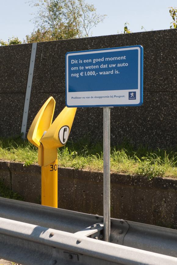 プジョーの屋外看板。ハイウェイの緊急電話の横に設置、「あなたの車に1,000ユーロの価値があるかを知る良い機会です」と買い替えを促がしてます。<オランダ>