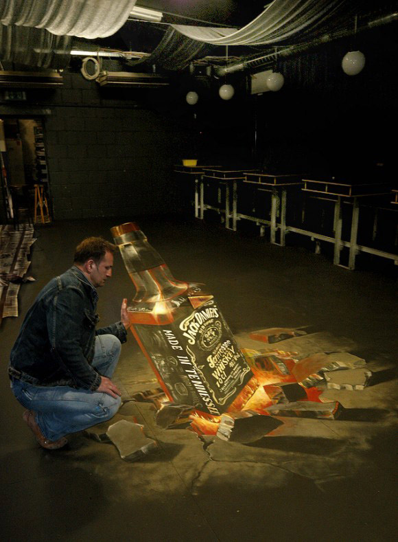 テネシー・ウイスキー＜ジャックダニエル＞の3Dストリートアート。地底から這い出そうな瓶を支えています。