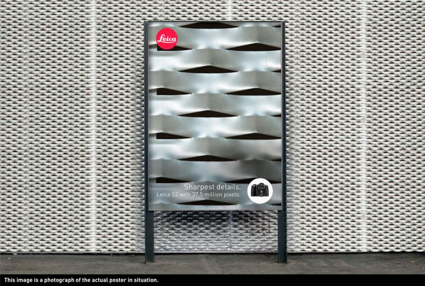 カメラ（ライカ）の屋外広告。金属壁のズームアップ写真をライカで写し、その鮮明さを表現しているようです。＜スイス＞